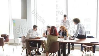 成功的多种族青年企业家团队在办公室共用一张桌子